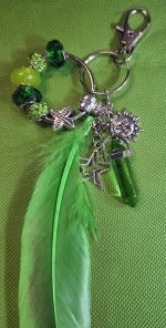 Handmade green feather bag charm with emerald and lime-green beads, silver-tone sun and star charms, green crystal-style pendant, keyring and lobster clasp.