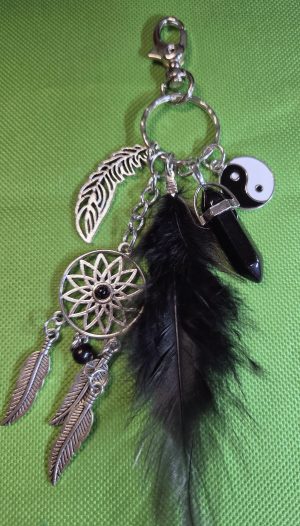 Handmade black dreamcatcher bag charm with long dark and gray feathers, turquoise-colored beads, silver-tone leaf, dreamcatcher, and dangling feather charms.